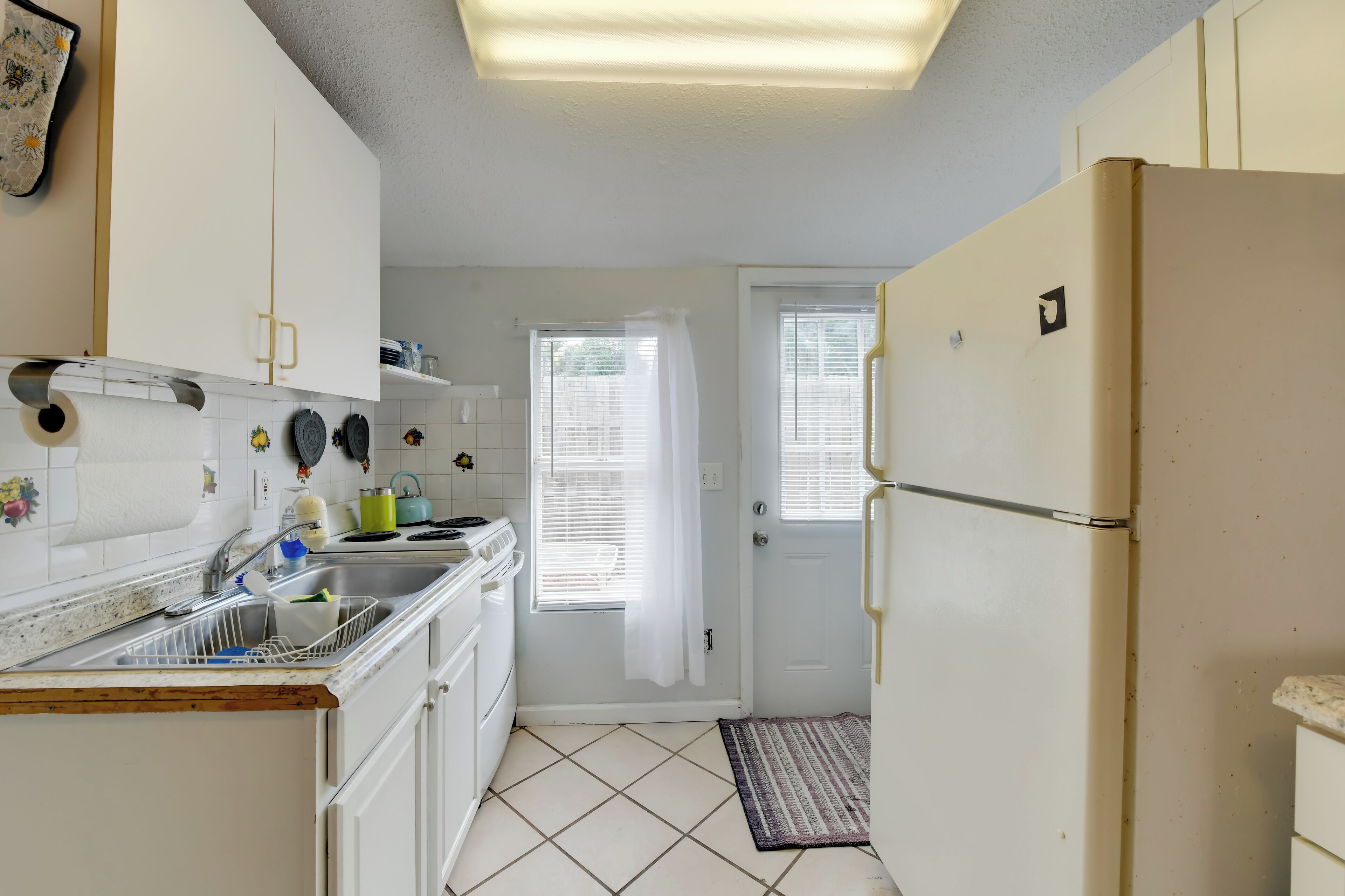 A compact kitchen with white cabinets, a sink, and a refrigerator.