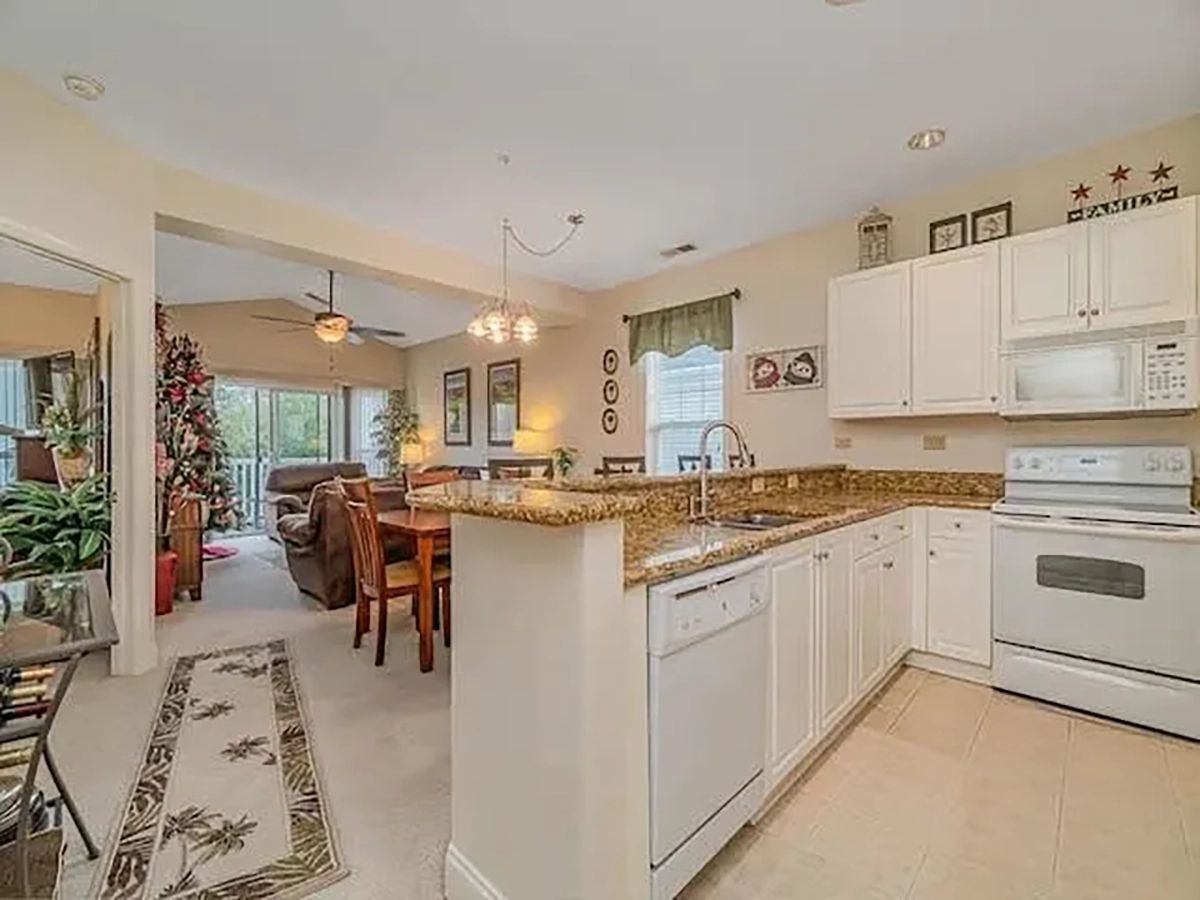 Kitchen with white cabinetry overlooking the adjacent dining area and living room.