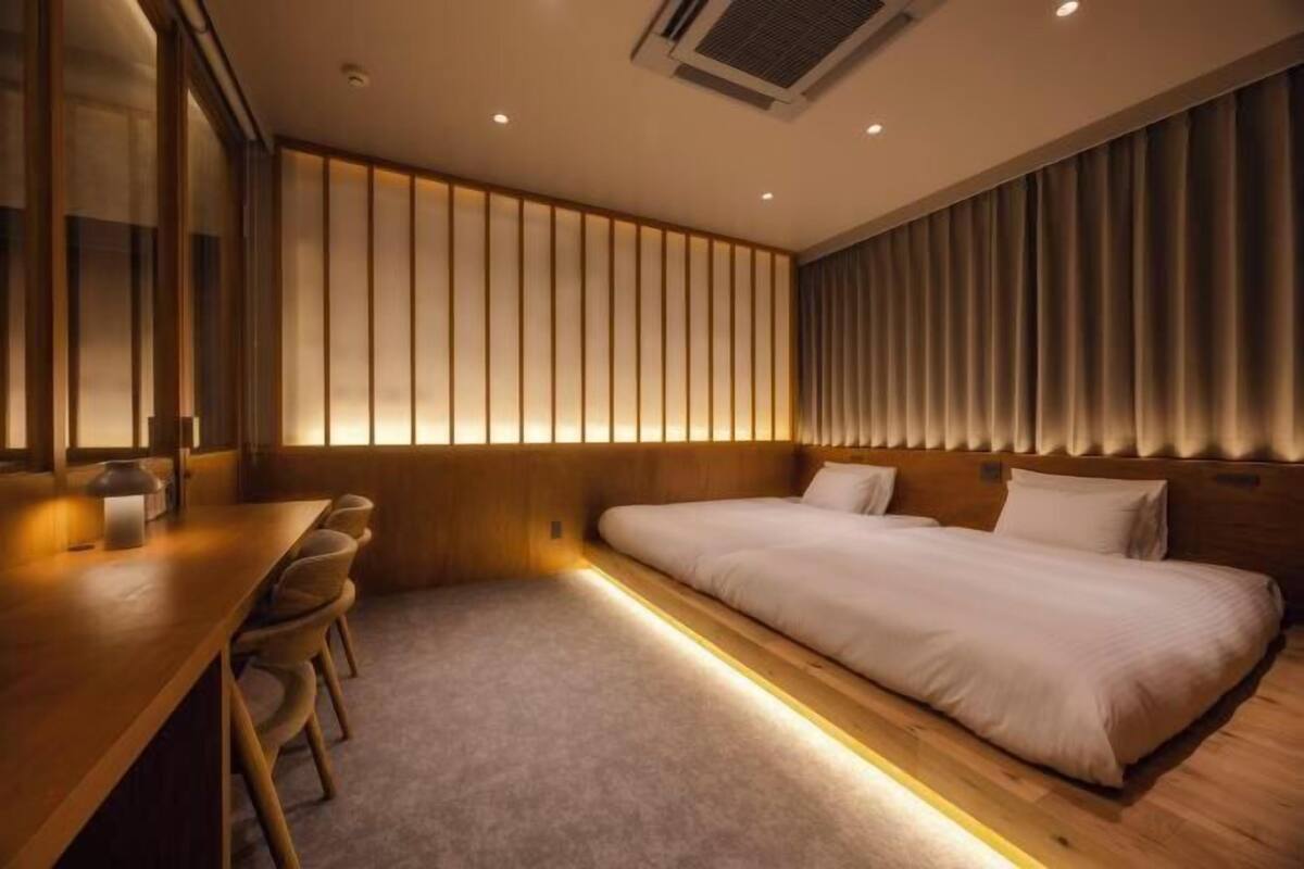 A modern hotel room with a large bed, a wooden desk, and a seating area.