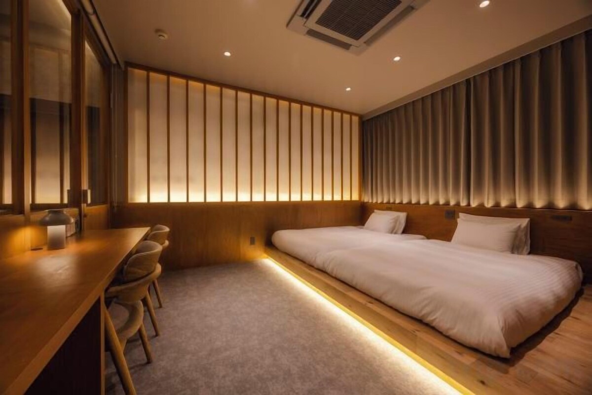 A hotel room with a bed, a desk, and chairs.