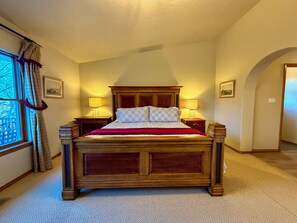 A bedroom with a wooden bed, two bedside tables with lamps, a window with curtains, and a framed picture on the wall. - Luxury Angel Fire 5BR 4B, Views!, Game Room (Angel Fire)