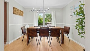 Un comedor con una mesa de madera, seis sillas, una araña y obras de arte en las paredes.