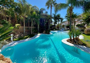 A clear blue pool surrounded by palm trees and a stone wall. - "Rincon de Marinos", a spacious house in a quiet estate, 5 mins. from the beach (Almuñécar)