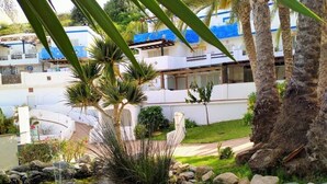 A landscaped garden with a water feature, palm trees, and a white building with blue accents. - "Rincon de Marinos", a spacious house in a quiet estate, 5 mins. from the beach (Almuñécar)