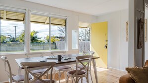 Un comedor con mesa y sillas, una puerta amarilla y vistas al exterior.