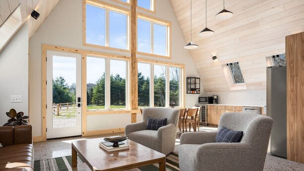 A spacious living room with a high ceiling, large windows, and a cozy seating area. - New A-Frame in wine country (Lake Leelanau)