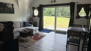 Una sala de estar con sofá, una mesa de centro y una zona de comedor con sillas y una mesa.