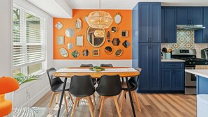 Un comedor con una mesa, sillas y una pared decorada con espejos y cuadros.
