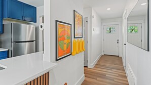 Una cocina moderna con refrigerador de acero inoxidable, armarios azules y encimera blanca.
