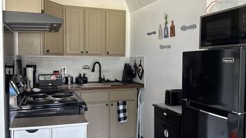A kitchen with a stove, microwave, and refrigerator. There are cabinets, a sink, and various kitchen utensils.