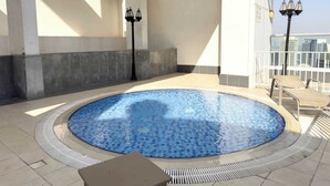 An indoor swimming pool with a tiled edge, a lounge chair, and two wall-mounted lamps. - Downtown Dubai Sleeps 2 Close to Dubai Mall (Dubai)