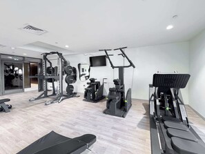 A modern gym with various exercise equipment, including a bench, weight machines, and a treadmill. - JVC Sleeps 2 Very Close to Five JVC (Dubai)