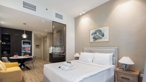 Une chambre d’hôtel moderne équipée d’un grand lit, d’un petit bureau, d’une chaise et d’une kitchenette.