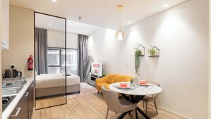Une chambre d’hôtel moderne comprenant un lit, une table à manger avec des chaises, un canapé, un coin cuisine et une salle de bain.
