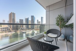 A balcony with a view of a city skyline and a river. There are wicker chairs and a small table. - Dubai Marina Sleeps 4 With Amazing Water Views (Dubai)