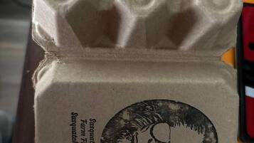 Eine aus Pappe gefertigte Eierverpackung mit aufgedrucktem Design und Text.