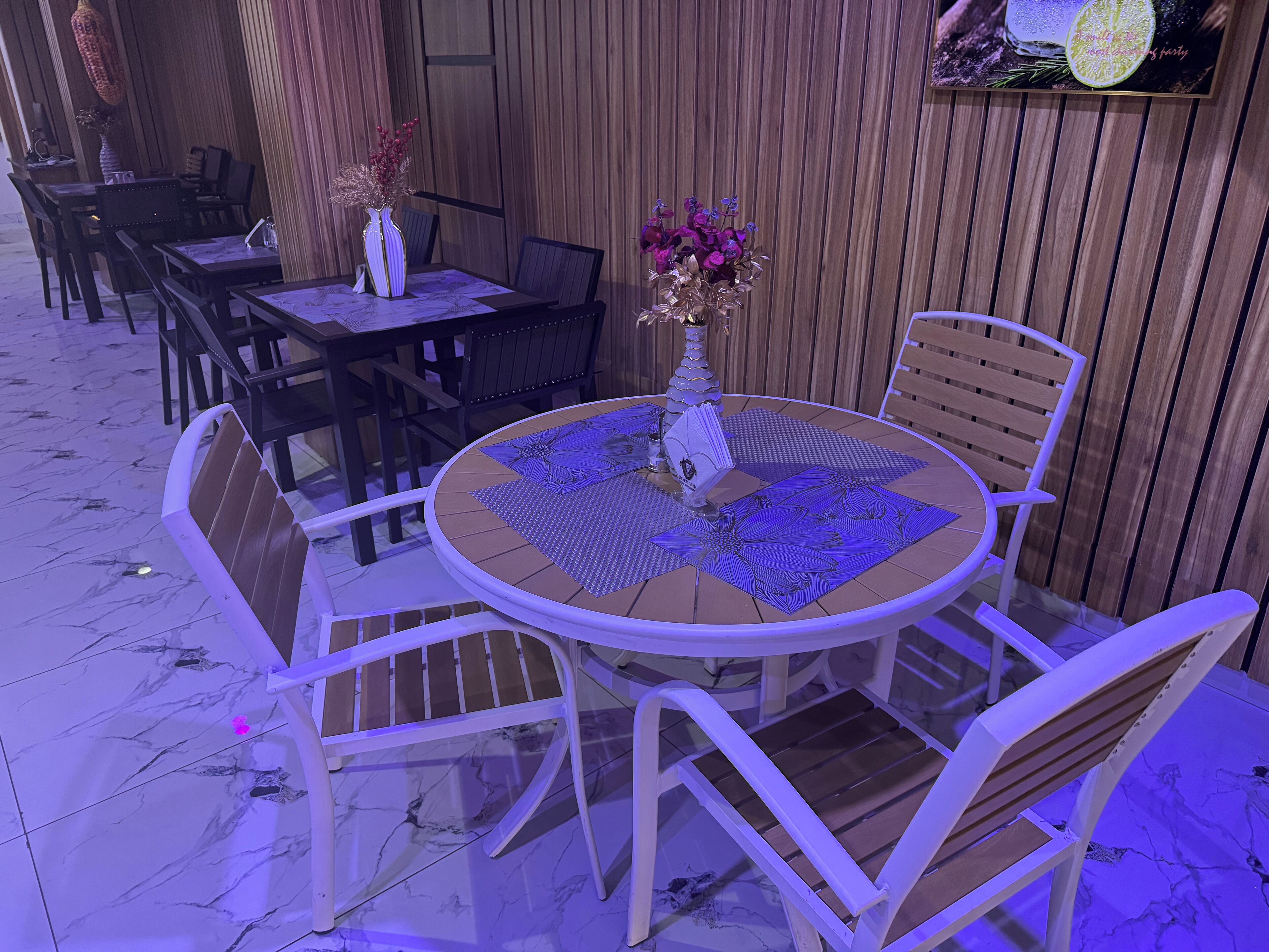 Een ronde tafel met een tafelkleed met bloemenprint, omringd door witte stoelen.