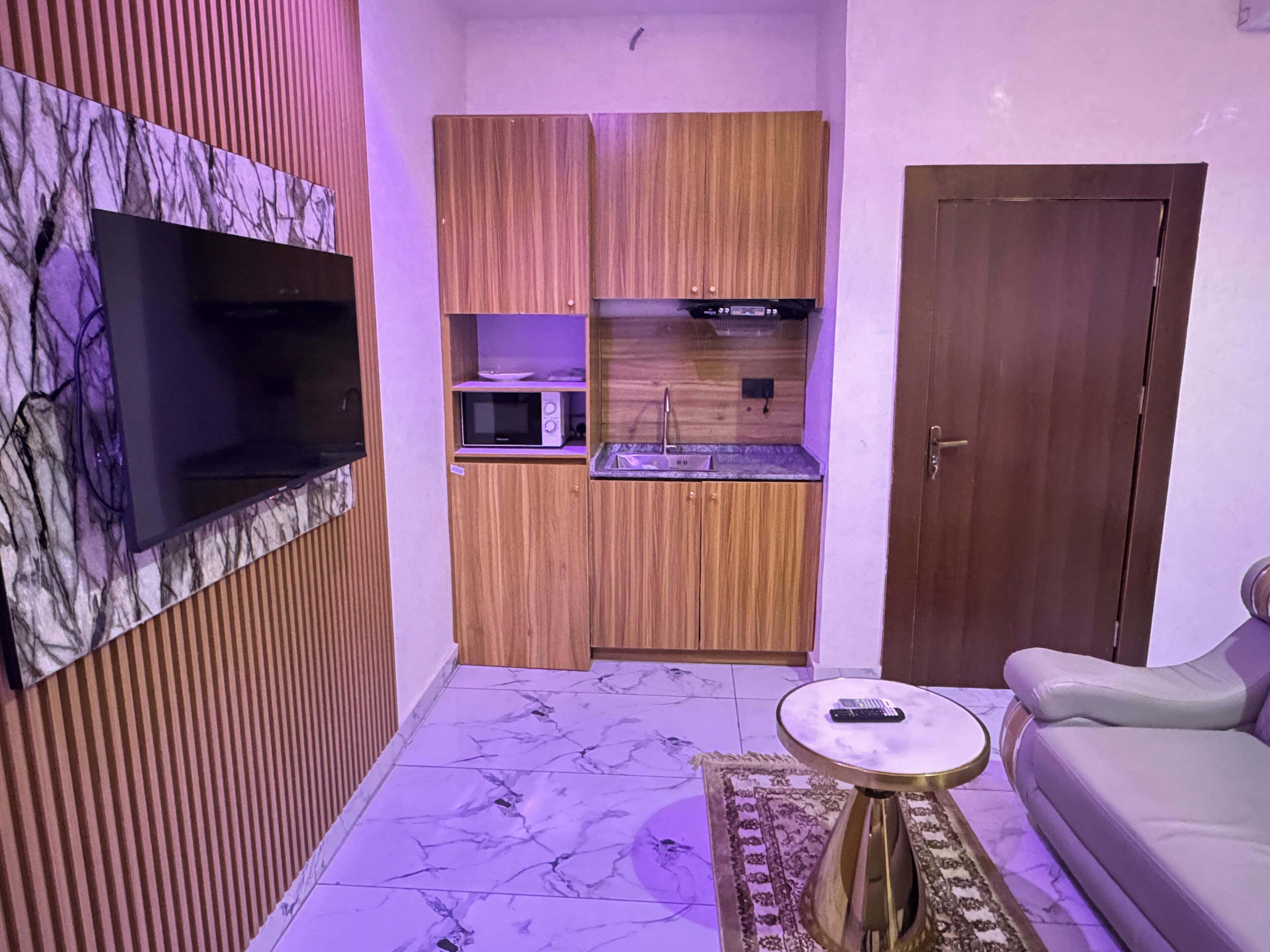 A compact living space with a kitchen area, a sofa, and a small table.