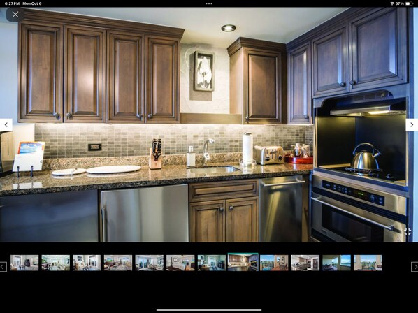 A modern kitchen with wooden cabinets, a granite countertop, stainless steel appliances, and a backsplash.
