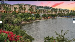 A resort with multiple buildings, a body of water, and lush greenery.