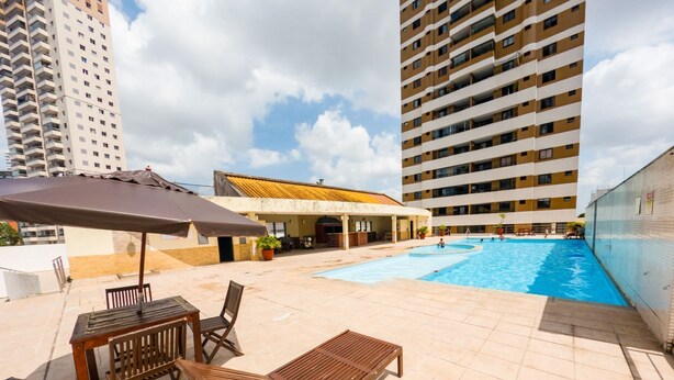 A rooftop pool area with lounge chairs and a covered seating area.