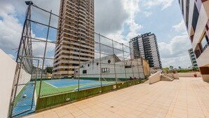 A rooftop sports court with a netted enclosure, surrounded by high-rise buildings.