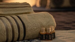 A neatly arranged bed with a striped pillow and two bottles of essential oils on a patterned bedspread. - Cozy Copacabana - Apt 407 - three minutes from Brazil's most famous beach (Rio de Janeiro)