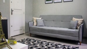 A living room with a grey sofa, a patterned rug, and a small Eiffel Tower model on a white table. - Cozy Copacabana - Apt 407 - three minutes from Brazil's most famous beach (Rio de Janeiro)