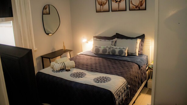 A neatly arranged bedroom with a bed, bedside table, and a mirror. - Cozy Copacabana - Apt 407 - three minutes from Brazil's most famous beach (Rio de Janeiro)