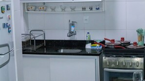 A kitchen with white cabinets, a black countertop, a stainless steel sink, a stove, and a shelf with glass bowls. - Cozy Copacabana - Apt 407 - three minutes from Brazil's most famous beach (Rio de Janeiro)
