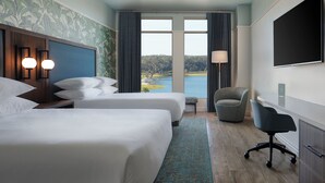 Une chambre d’hôtel avec deux lits, un bureau, une chaise, une télévision et une vue sur l’eau.