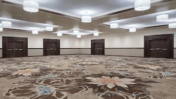 A large, carpeted room with a floral pattern, multiple doors, and ceiling lights.