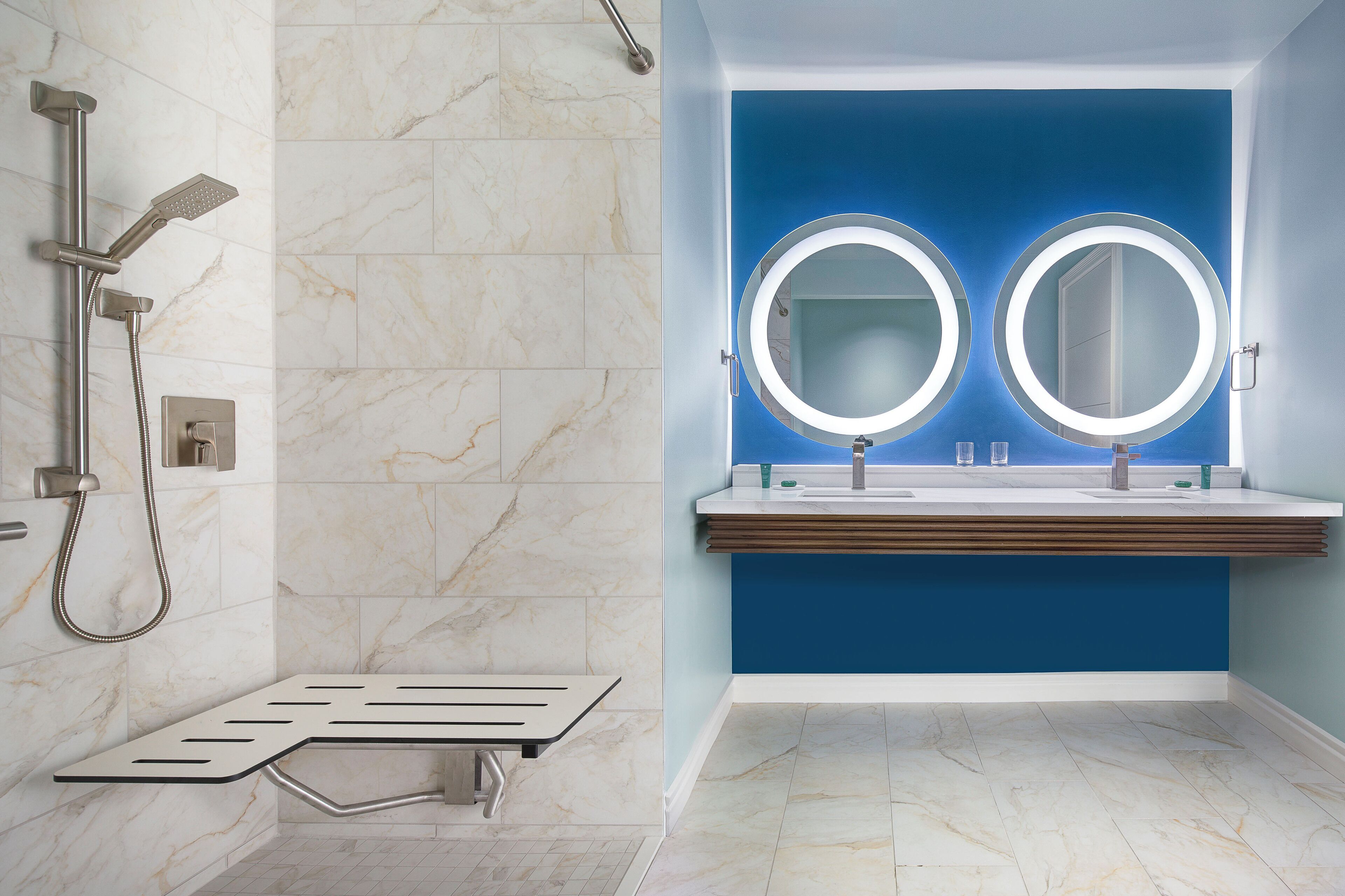 A modern bathroom with a shower, two round mirrors, and a wooden vanity.