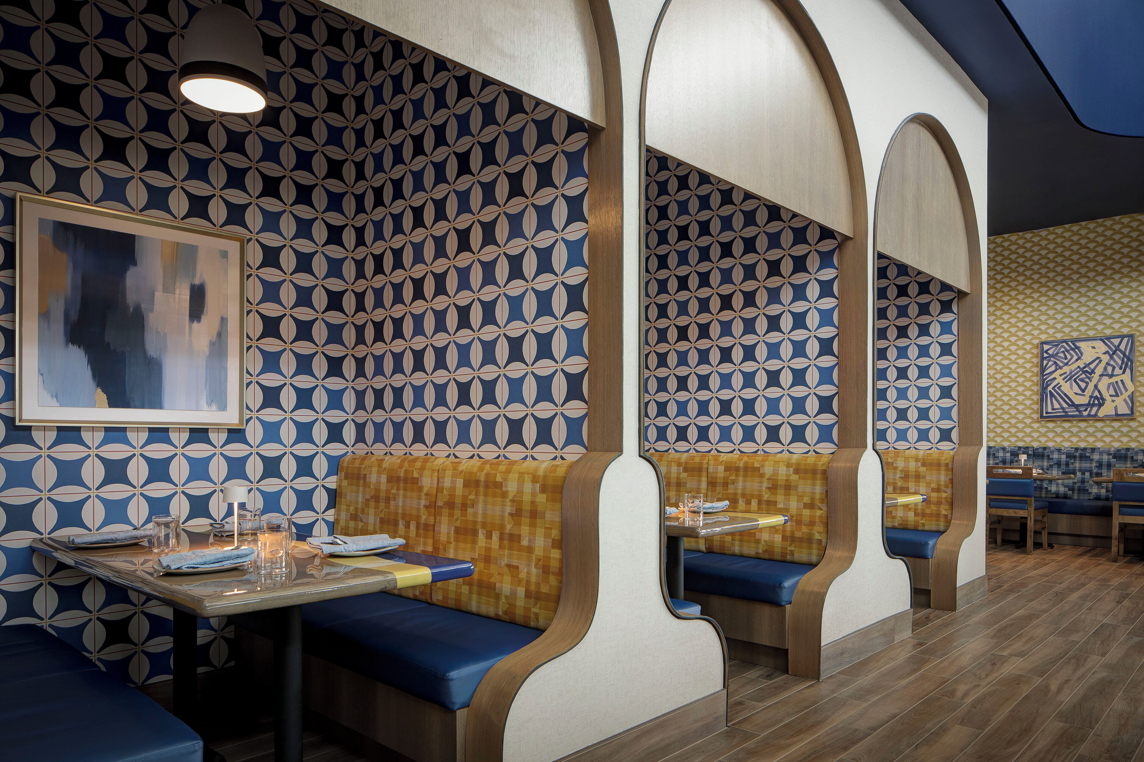 En restaurang med ett inredningskoncept som inkluderar väggar med mönster, träbeklädda bås och ett område för matgäster.