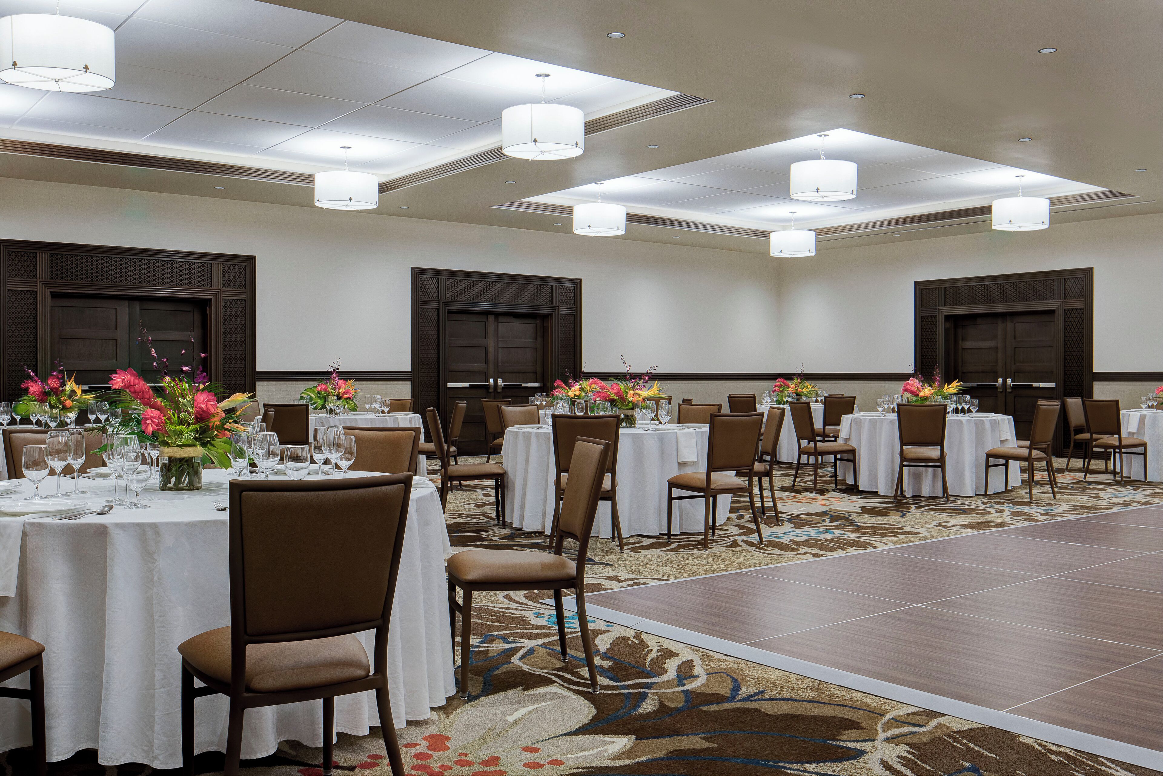 Un salón de banquetes con mesas redondas, sillas y una pista de baile.