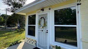 Uma casa com porta branca, número 5445, e uma guirlanda na porta.
