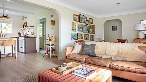 Una sala de estar con un sofá, una mesa de centro y una estantería. Hay una zona de cocina con estufa y refrigerador.