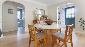 Un comedor con una mesa redonda, sillas de madera y una lámpara central.
