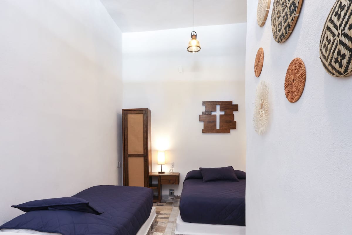 Un dormitorio con dos camas, una mesita de noche, una lámpara y decoración en la pared.