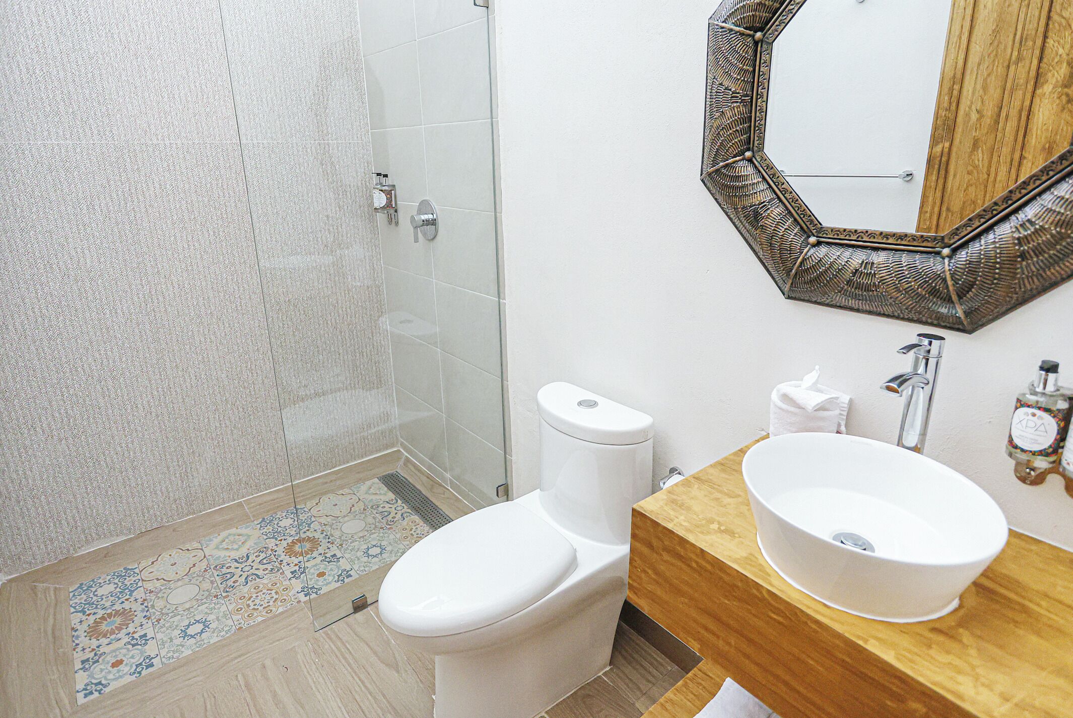 A bathroom with a toilet, sink, mirror, and shower.