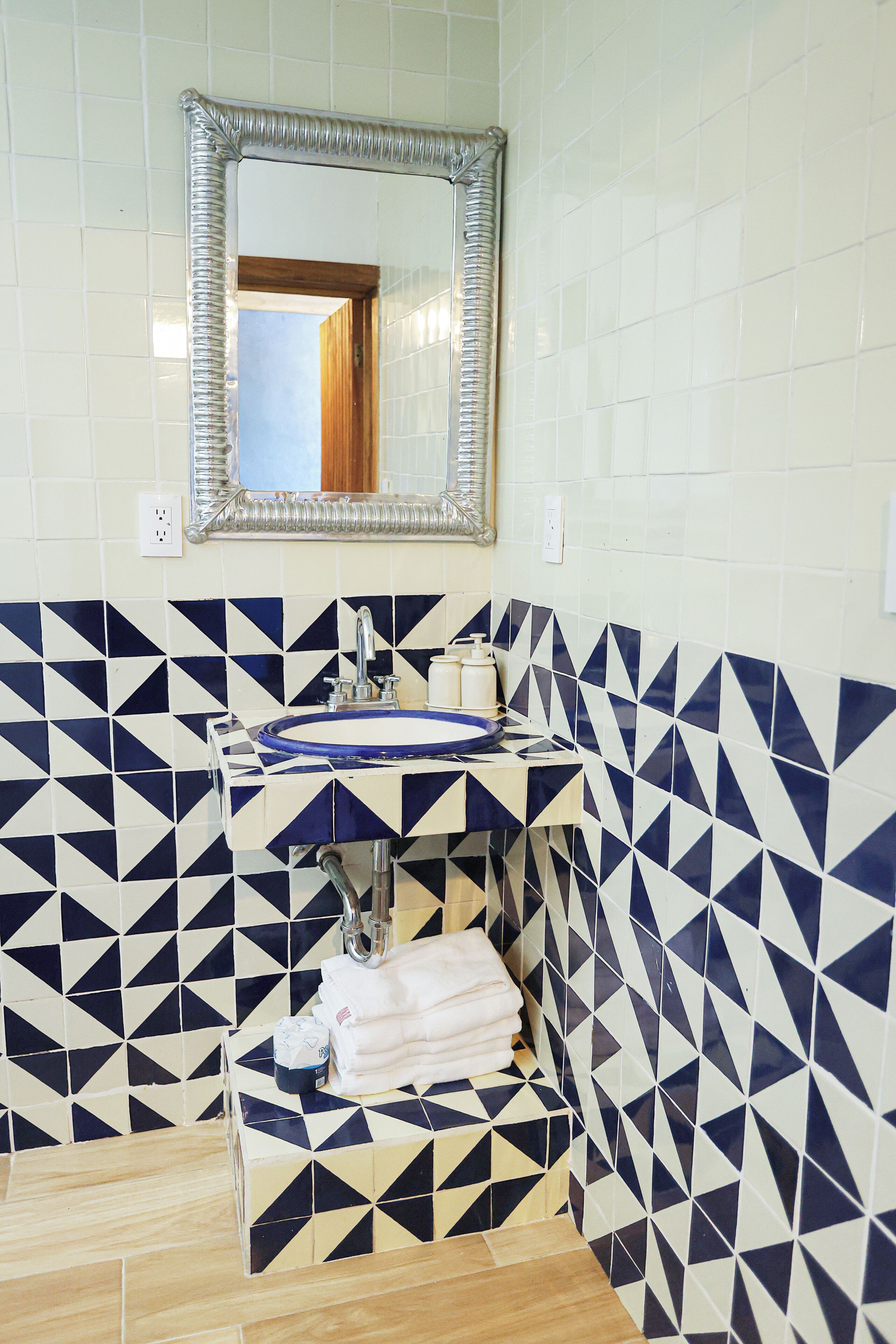 A bathroom with a sink, mirror, and geometric patterned tiles.