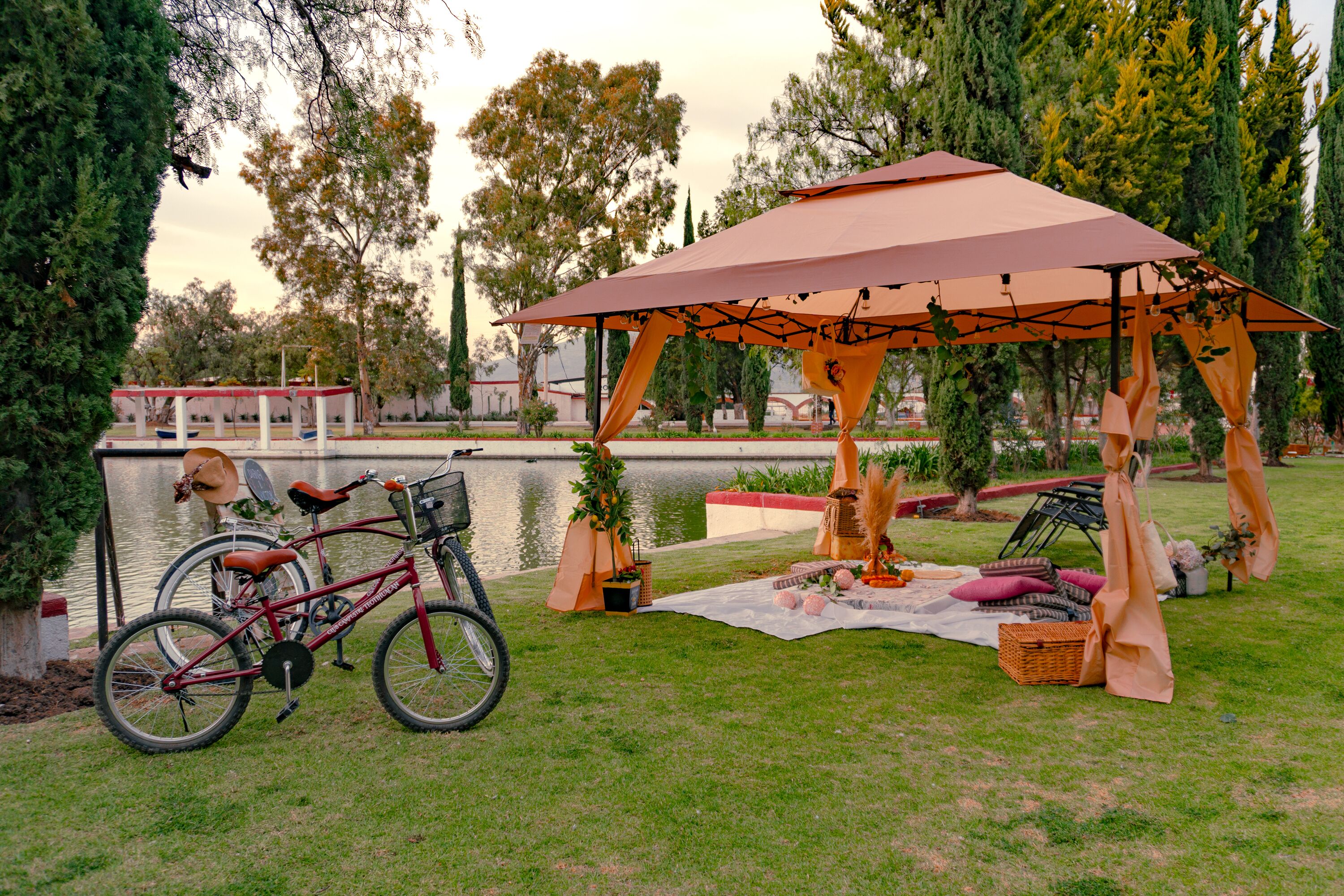 Un pabellón con toldo, una bicicleta y una disposición para picnic junto al agua.