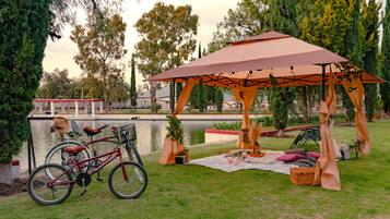 Un pabellón con toldo, una bicicleta y una disposición para picnic junto al agua.