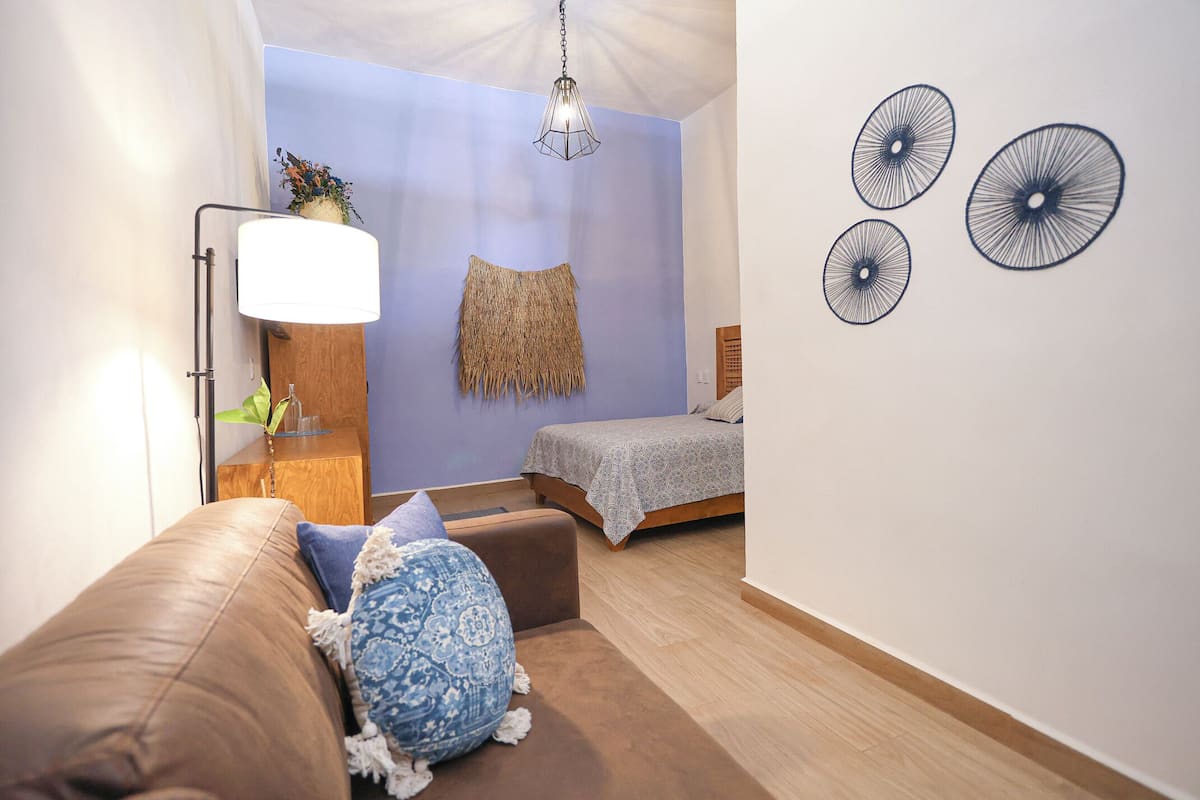 Un dormitorio con cama, mesita de noche, lámpara, un adorno en la pared y luz de techo.