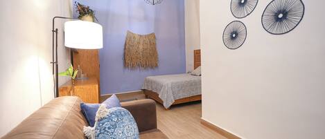 Un dormitorio con cama, mesita de noche, lámpara, un adorno en la pared y luz de techo.