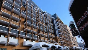 Un hôtel à plusieurs étages doté de balcons, une enseigne indiquant « CHOC » et un magasin d’alimentation « SPAR ».
