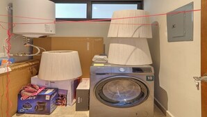 A laundry room with a washing machine, a dryer, and a large window. - Apratamento Salinas Emerald - Yucatan Home Rentals (Progreso)