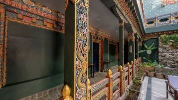 A traditional interior with ornate columns, a stone wall, and a wooden railing.