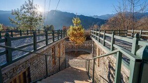 Un escalier en pierre avec une rampe en bois menant à une plateforme d’observation dotée d’une balustrade en métal.