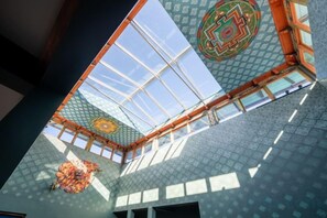 Een hoge plafond met dakraam, muren met een patroon en een geometrisch ontwerp op het plafond.